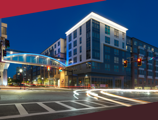 An apartment building exterior at dusk showing moving traffic - JAG Management Company Jefferson Apartment Group property manager jobs